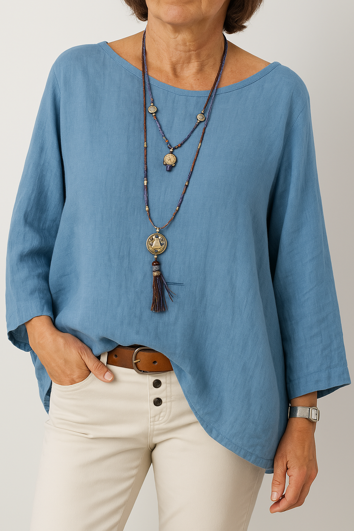 Front view, model wearing a blue oversized cotton-linen tunic with a boat neck and three quarter sleeves