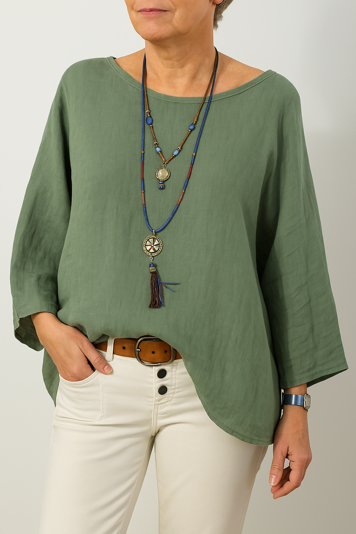 Front view, model wearing a green oversized cotton-linen tunic with a boat neck and three quarter sleeves