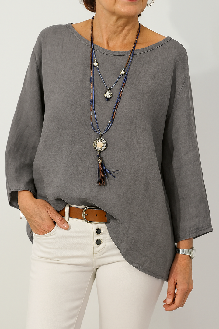 Front view, model wearing a grey oversized cotton-linen tunic with a boat neck and three quarter sleeves