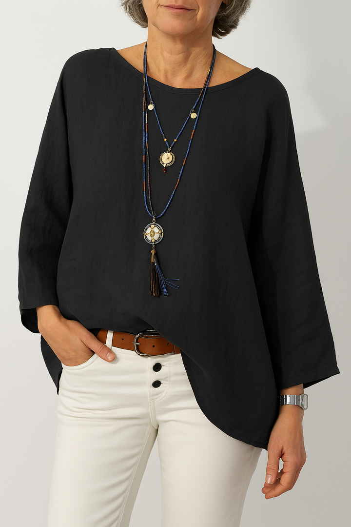 Front view, model wearing a black oversized cotton-linen tunic with a boat neck and three quarter sleeves