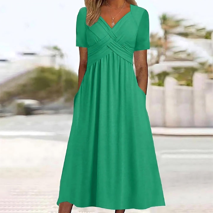 Front view of the green Evelyn midi dress worn by a model, showing the elegant A-line cut and pockets