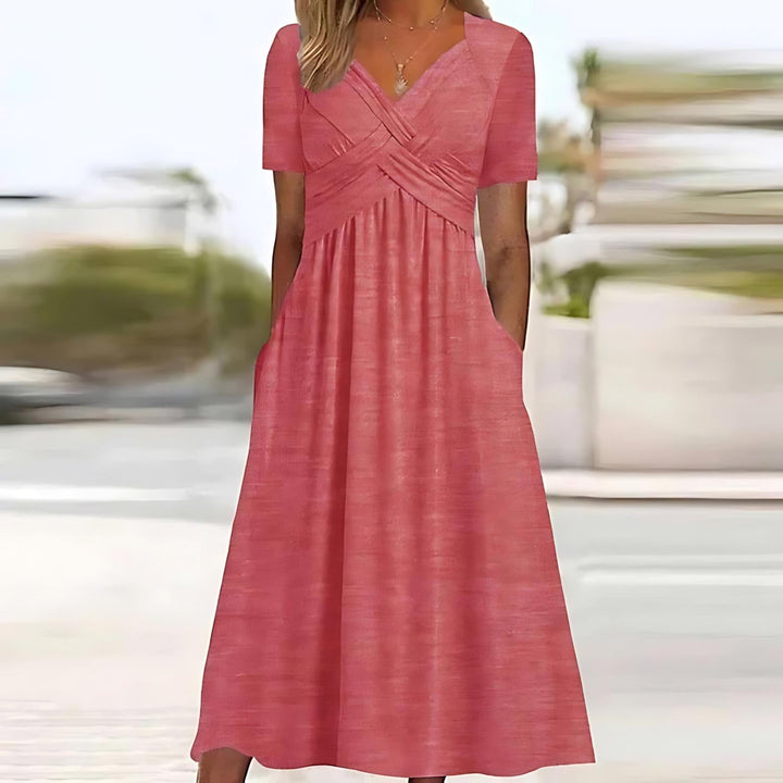Front view of the coral Evelyn midi dress worn by a model, showing the elegant A-line cut and pockets
