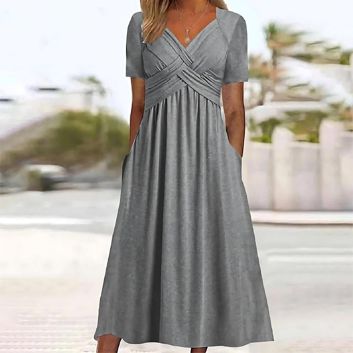 Front view of the grey Evelyn midi dress worn by a model, highlighting the short sleeves and side pockets