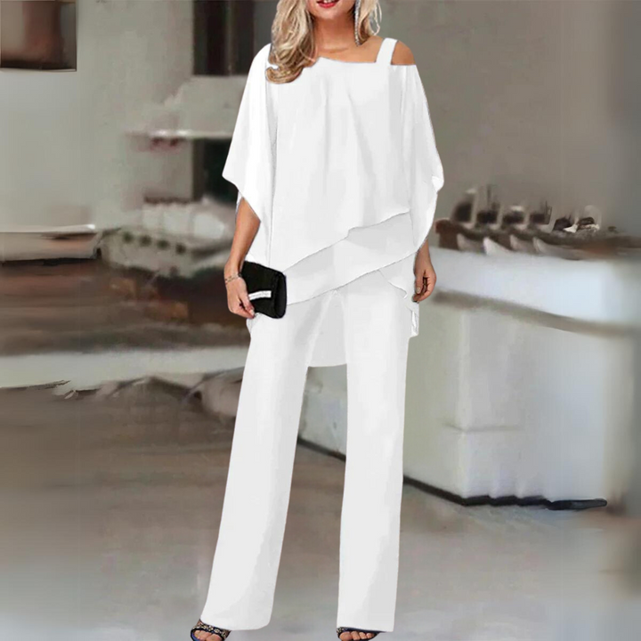 Front view, model in white elegant straight-leg trousers and flowing top set with black clutch and heels