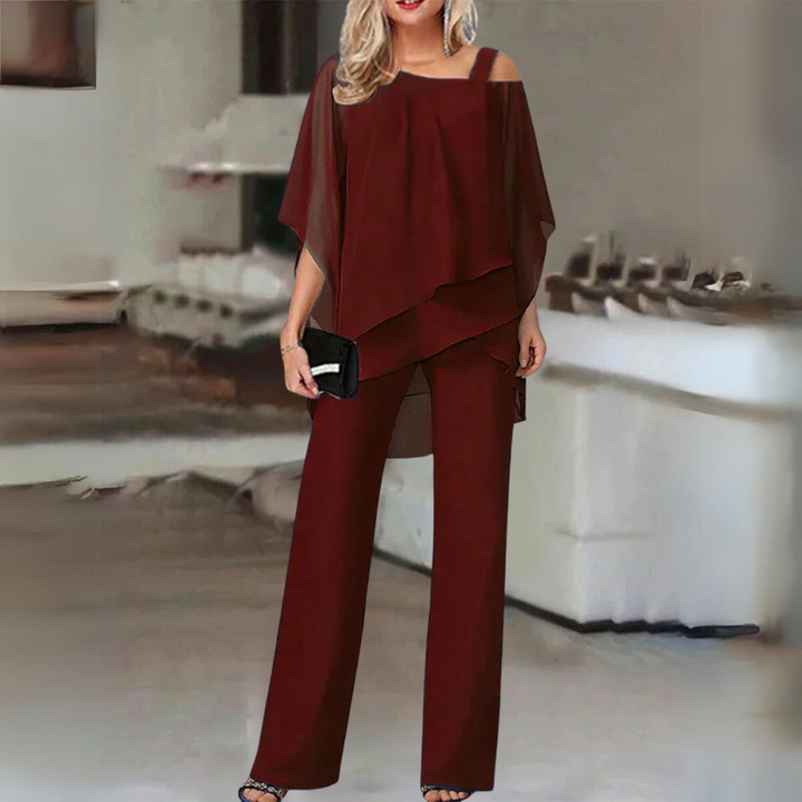 Front view, model in elegant straight-leg trousers and flowing top set in rich burgundy with black clutch and heels