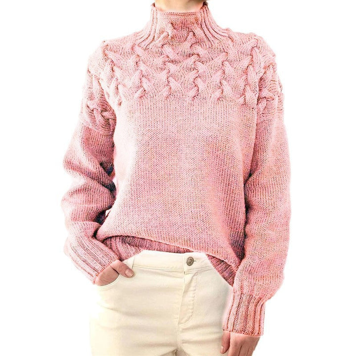 Front view of a model wearing a pink cable knit mock neck sweater with cream trousers, hand in pocket