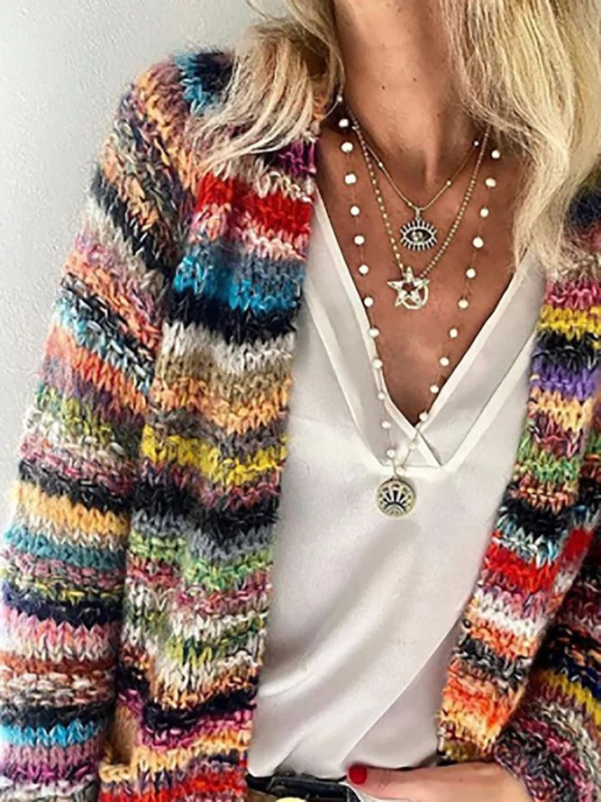Close up, worn by model, showing the vibrant Icelandic pattern sweater with a white top and layered necklaces