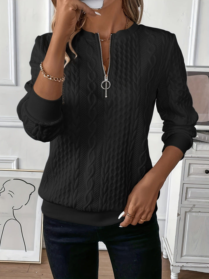 Front view worn by model, a black cable knit zip sweater with a silver ring pull, paired with dark jeans