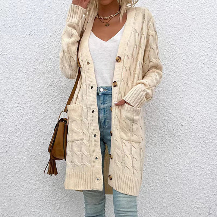 Front view of a model in a long cream cable knit cardigan with button front, pockets, and ribbed cuffs