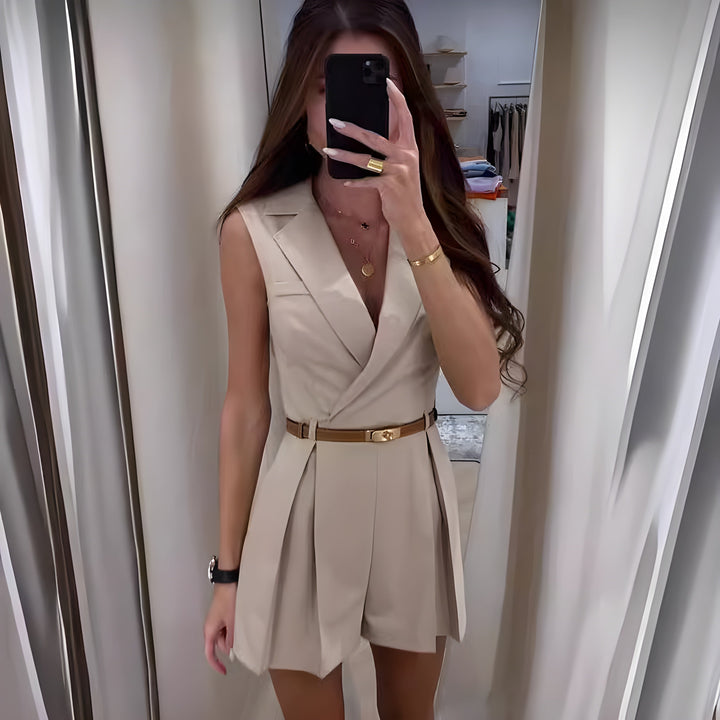 Front view of a woman wearing the elegant summer jumpsuit, with a brown belt, taking a mirror selfie