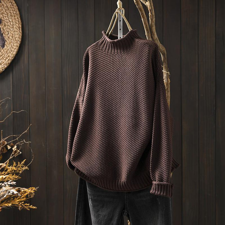 Front view of a brown textured knit sweater, an oversized autumn pullover hanging on a branch with dark jeans