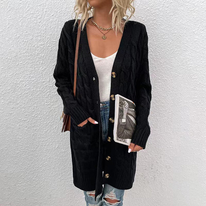 Front view of a model in a long black cable knit cardigan with button front, pockets, and ribbed cuffs