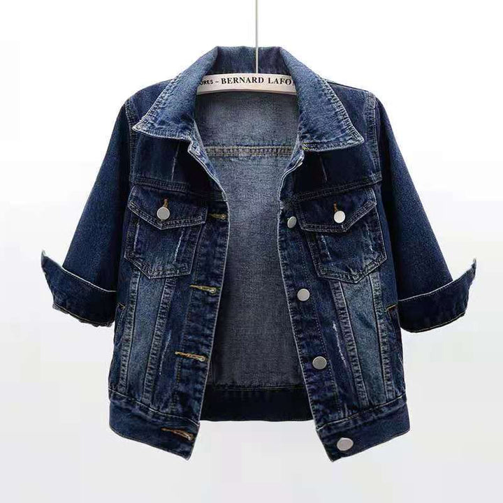 Front view of a dark blue colourful denim jacket with rolled up three quarter sleeves, on a hanger