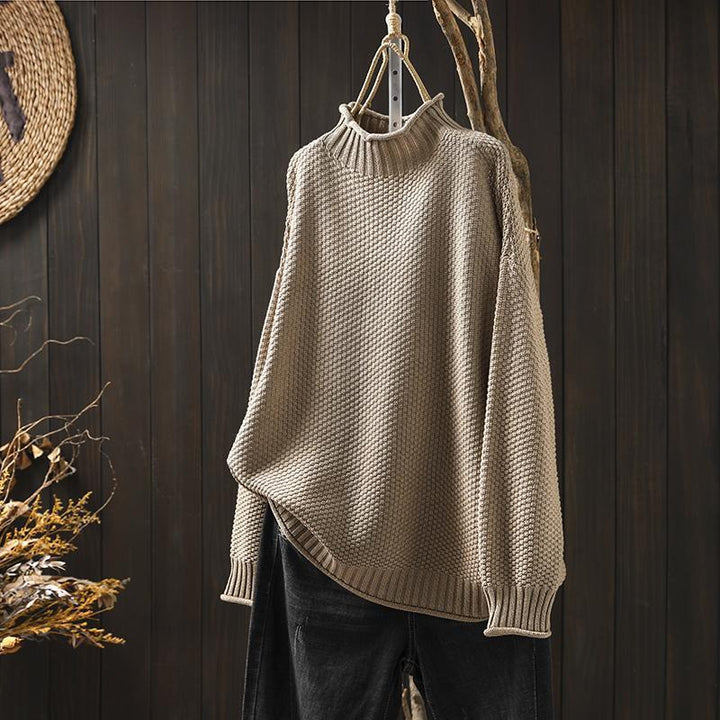 Front view of a beige textured knit sweater, an oversized autumn pullover hanging with black jeans