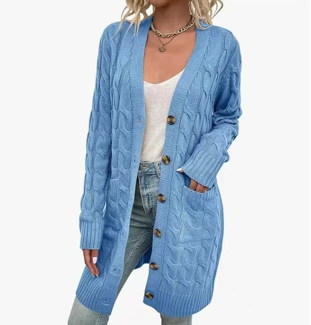 Front view of a model in a long light blue cable knit cardigan with large buttons, pockets, and ribbed cuffs