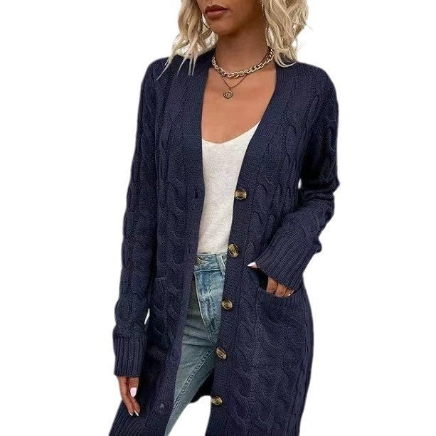 Front view of a model in a long navy blue cable knit cardigan with large buttons, pockets, and ribbed cuffs