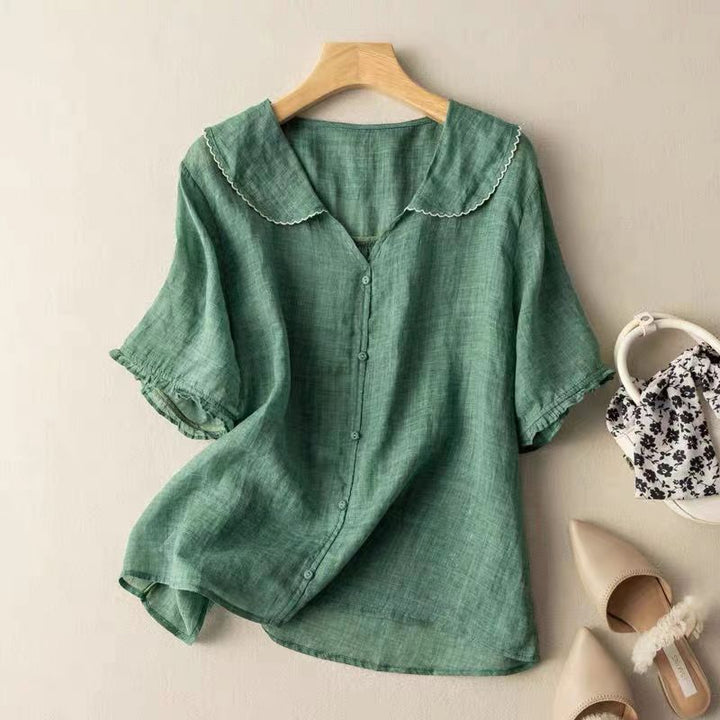 Front view of a green lightweight linen blouse with a white scalloped collar and short sleeves on a hanger