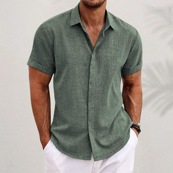 Front view of a man wearing a relaxed fit green linen shirt with rolled sleeves and white pants