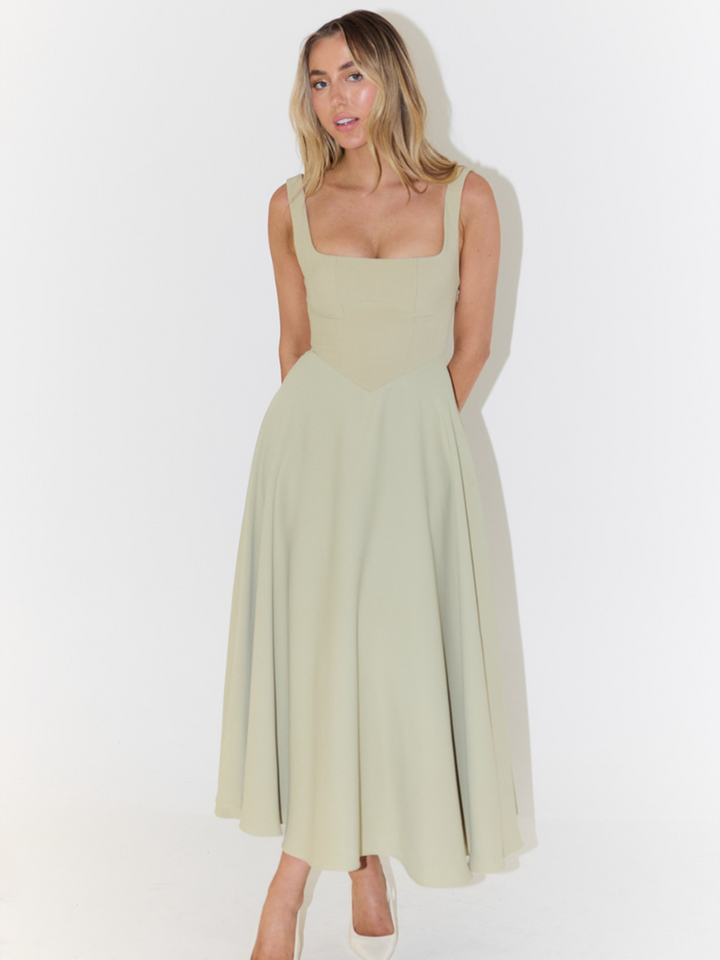 Elegant long dress front view worn by model, square neckline and full skirt, hands behind back