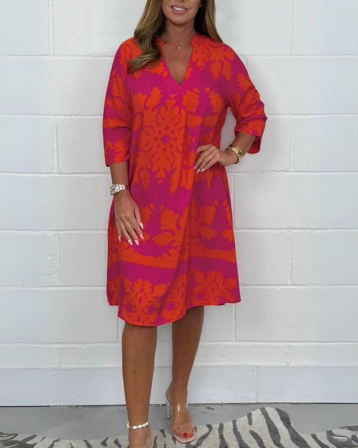 Front view of a woman wearing a pink and orange patterned boho V-neck midi dress with 3/4 sleeves