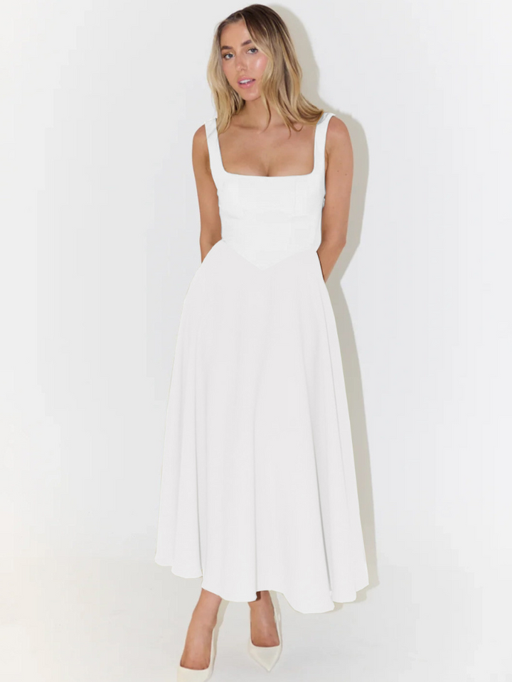 Elegant long dress front view worn by model, square neckline, full skirt, hands behind back, looking at, alternate angle