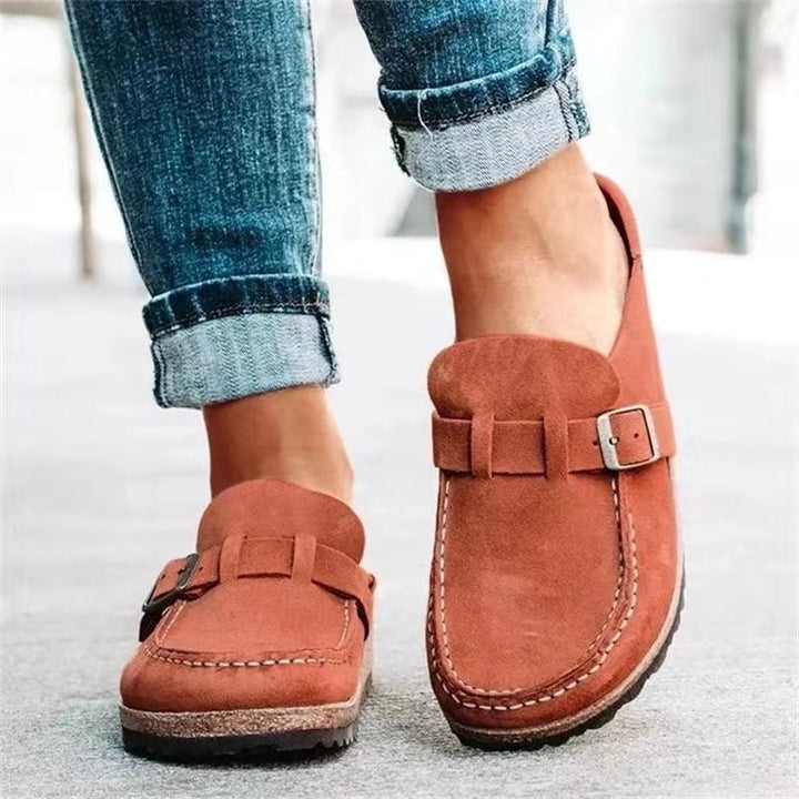Worn by model of terracotta suede loafers with buckle and white stitching detail, paired with cuffed jeans