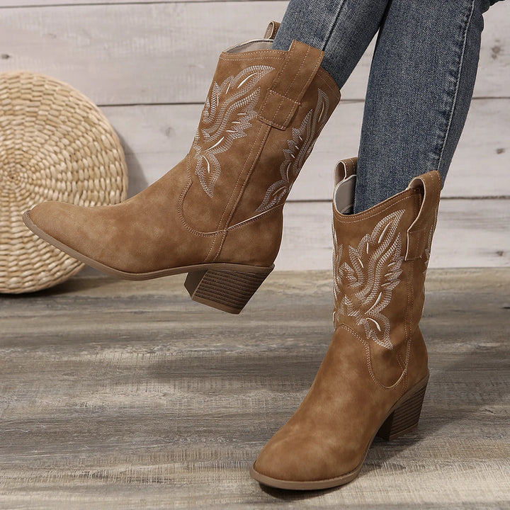 Pair of tan western ankle boots worn by model, showing embroidered shafts and pointed toes