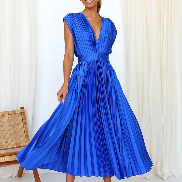 Front view, model wearing a royal blue Felicia pleated dress with a deep V neckline and cap sleeves