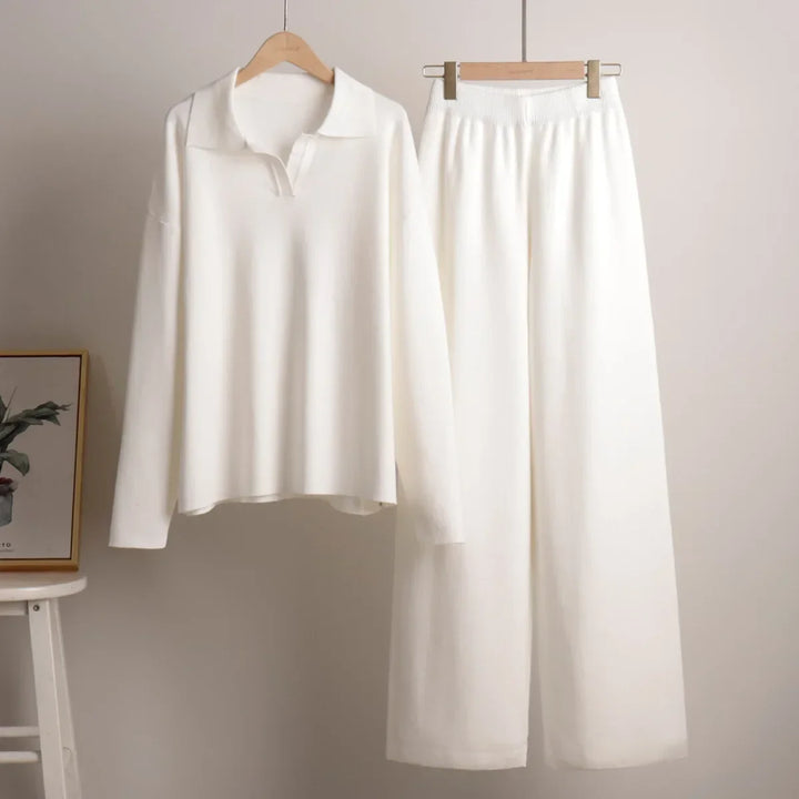 Flat lay of a cream cozy knitted two-piece set, with a polo neck sweater and wide-leg pants on hangers