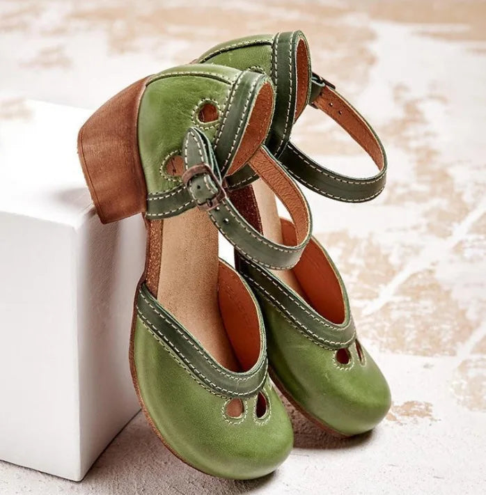 Three quarter view of a pair of green retro colour-block sandals with buckle straps and a mid-heel, on a white block