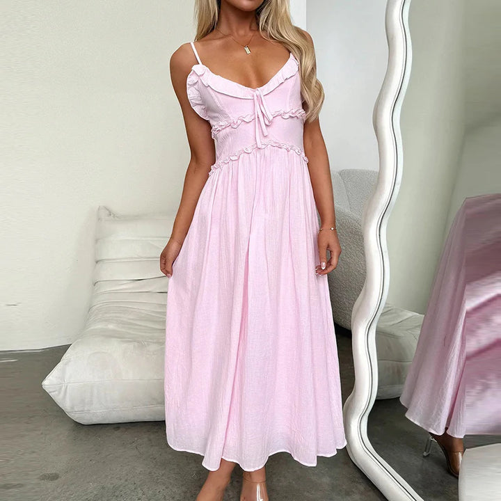 Front view, model wearing a pink pleated V-neck beach dress with tie front detail and ankle length A-line skirt