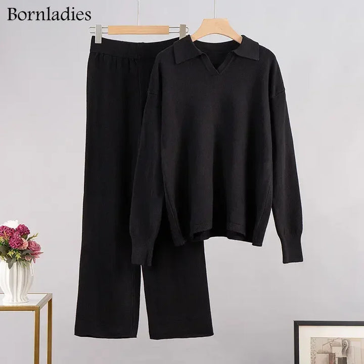 Flat lay of a black cozy knitted two-piece set, featuring a polo neck sweater and wide-leg pants on hangers