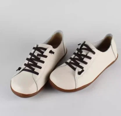 Three quarter view of a pair of Nora genuine leather flats in cream with dark brown laces and soles