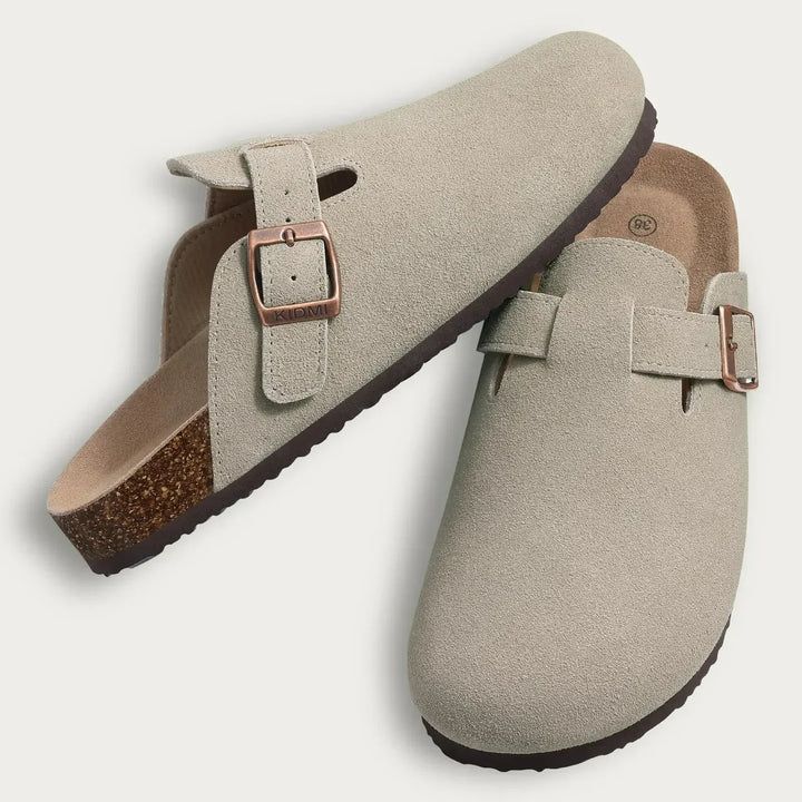 Close up of light beige Aaron slip-on sandals, suede upper, bronze buckles, cork footbed, flat lay
