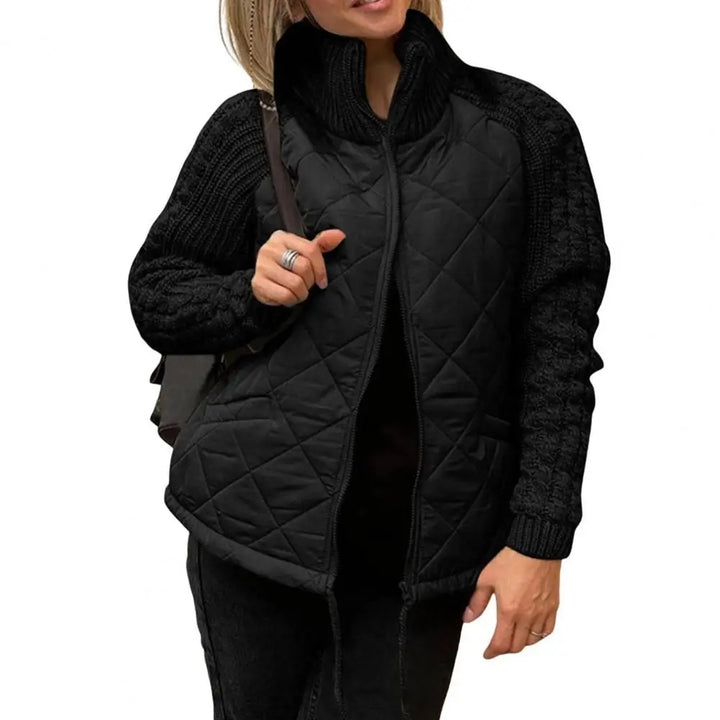 Front view worn by model, a woman wearing a black quilted knit jacket with an open zip and high collar