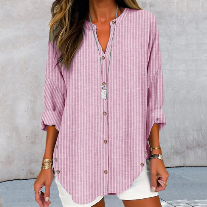 Front view of a model wearing the Kaia printed button blouse in pink and white stripes with a long necklace