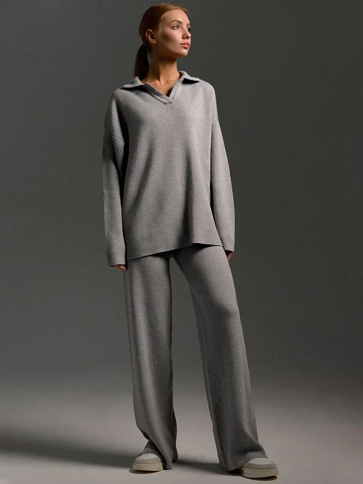 Full length view of a model in a grey cozy knitted two-piece set, featuring a polo neck sweater and wide-leg pants