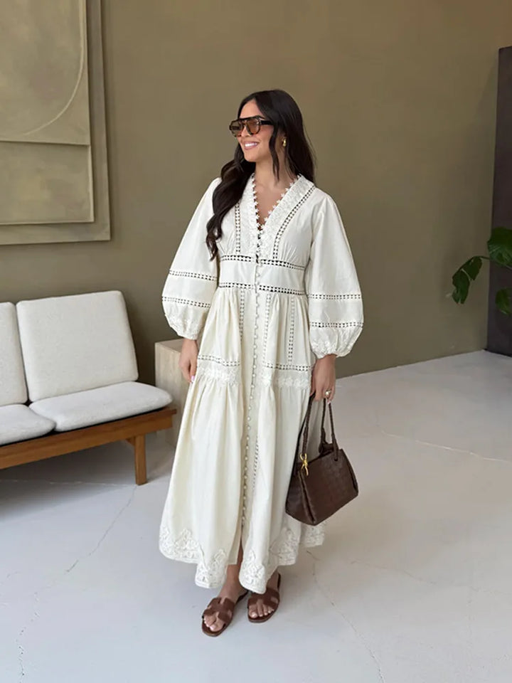Front view, worn by model, of an elegant lace patchwork dress in cream, with long sleeves and a V-neckline