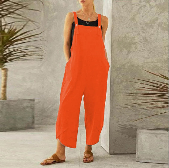 Front view of a model wearing the bright orange Isla oversized cotton-linen summer overalls with hands in pockets