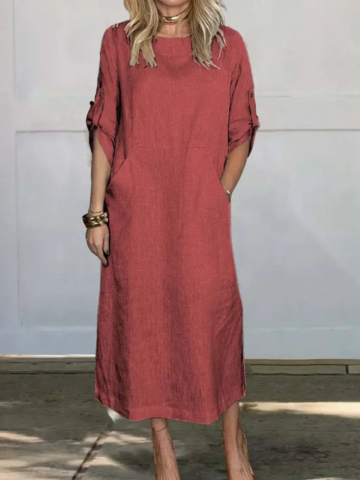 Front view of the Emma Linen Midi Dress in rust, worn by a model with hands in side pockets