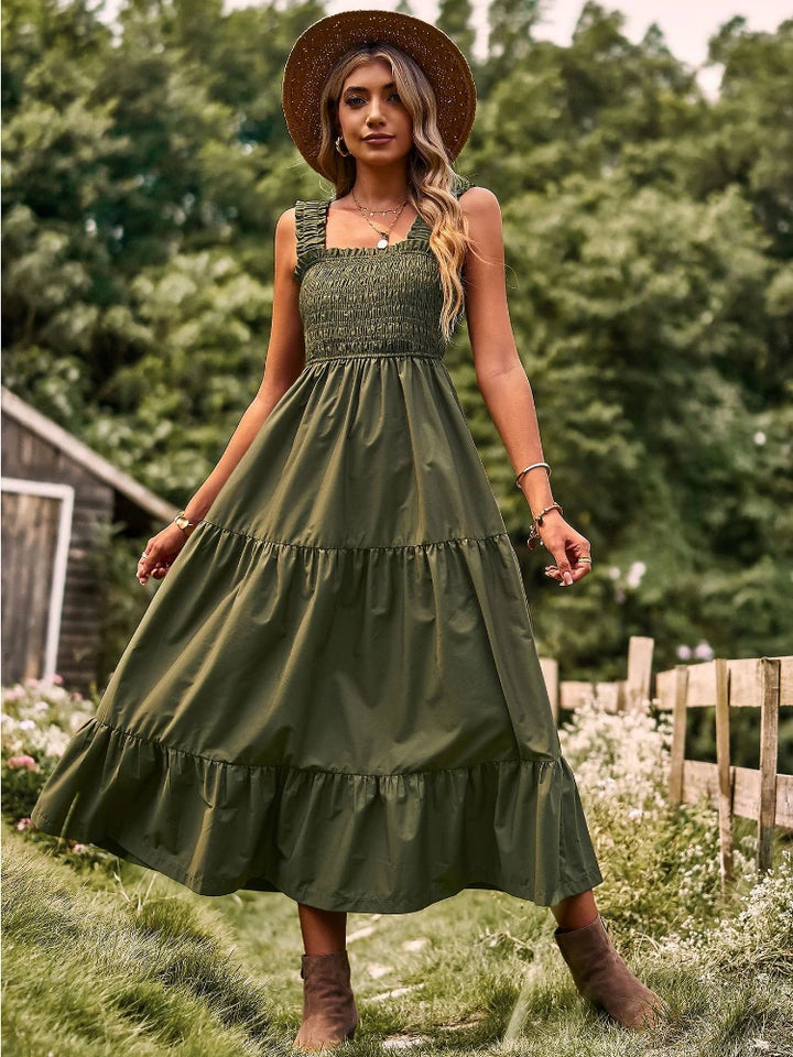 Front view of a model in a green sleeveless halter maxi dress with a square neckline and tiered skirt