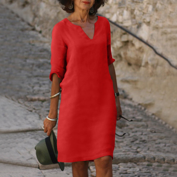 Front view of a woman wearing a red vintage solid mini dress with three-quarter sleeves on stone steps