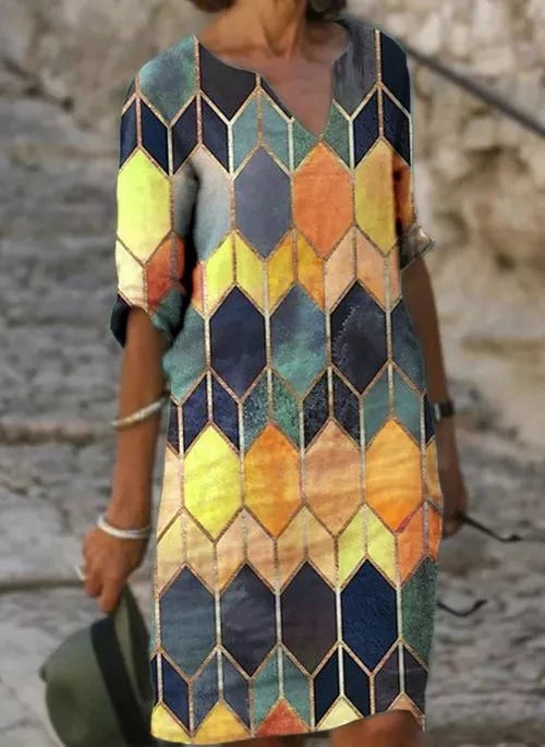 Front view worn by model of a vintage printed summer dress with a colourful geometric pattern