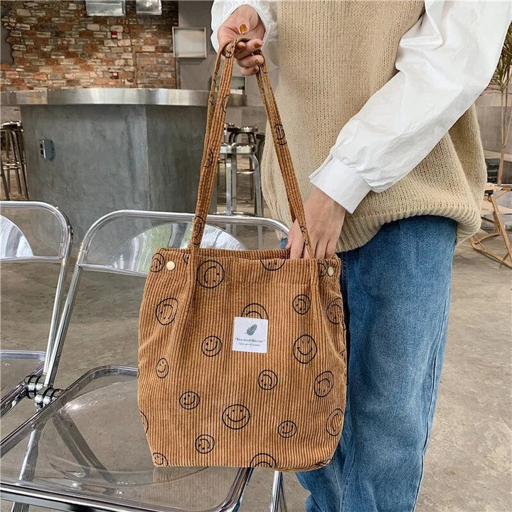 Front view of a model holding the Smiley Print Corduroy Tote Bag with both hands