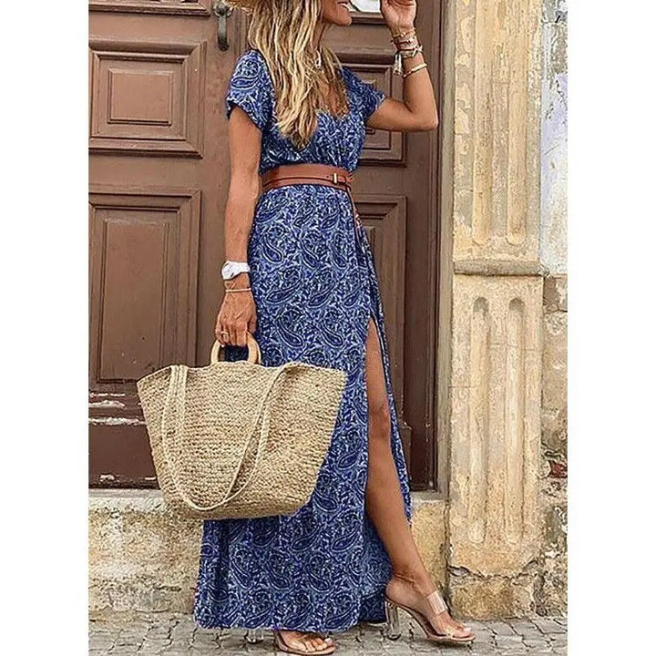 Three quarter view of a model wearing the floral pleated midi dress with a straw hat and woven bag