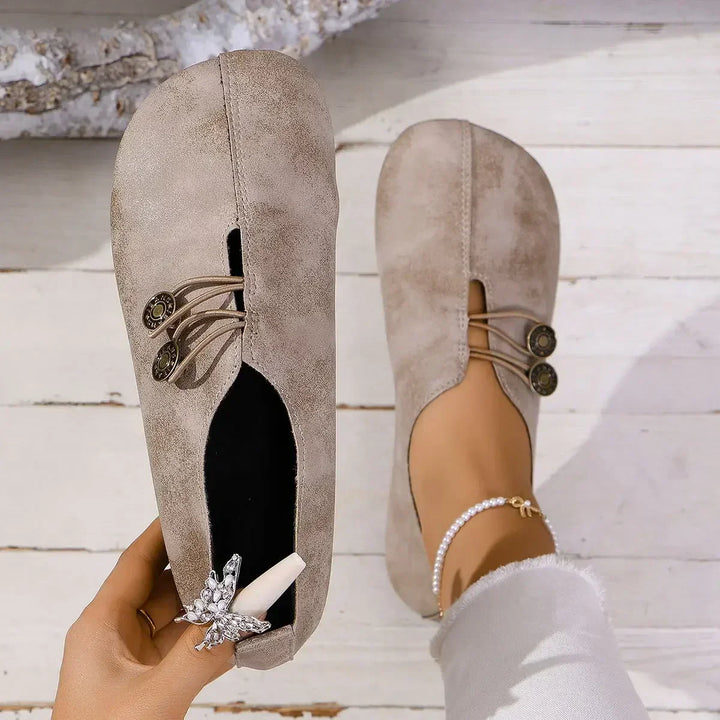Top view of a beige soft suede loafer held by hand and one worn by model with a pearl anklet