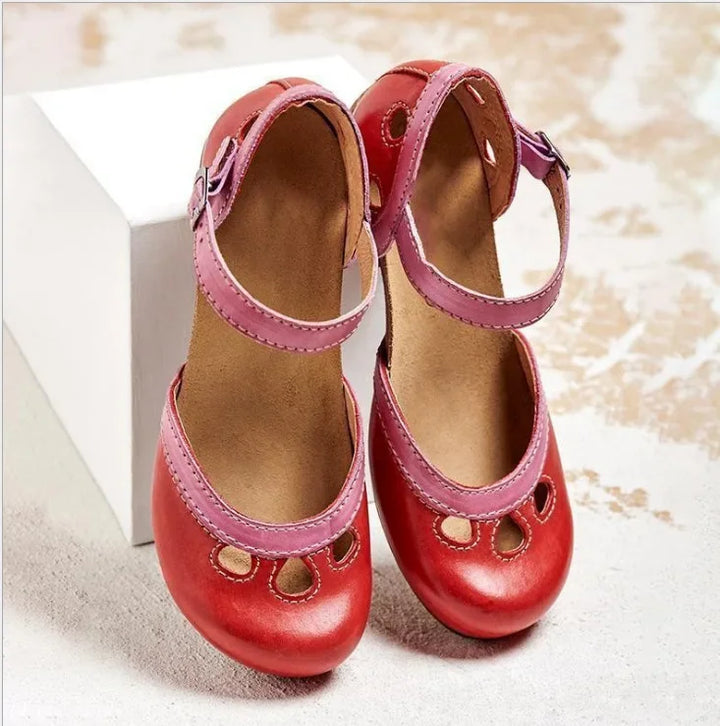 Close up front view of red retro colour-block sandals with pink buckle straps and decorative cut-outs