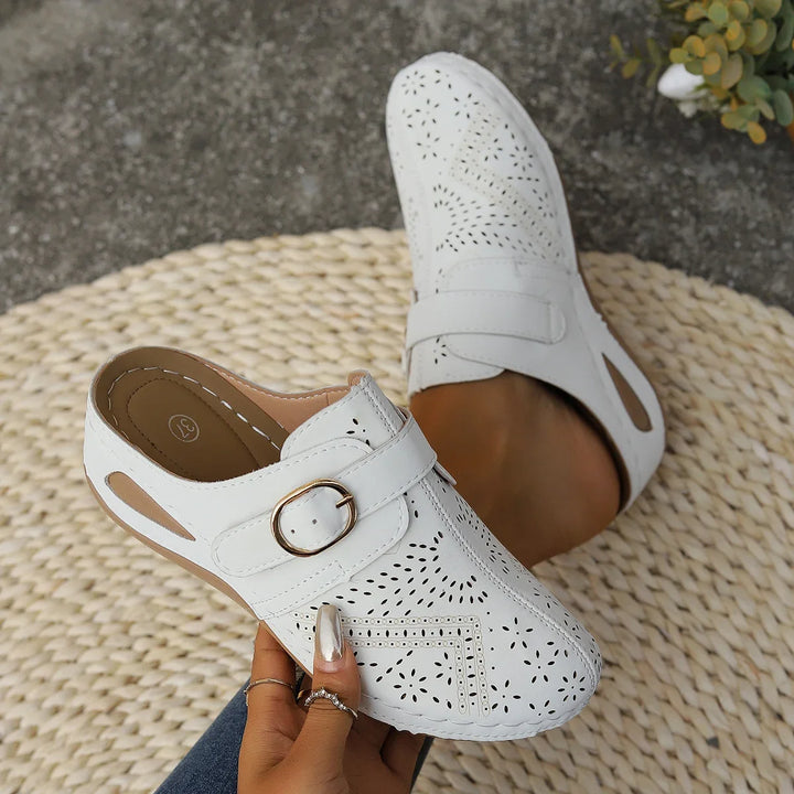 Close up of white orthopaedic summer slides with perforated detail, one worn by model, one held by model