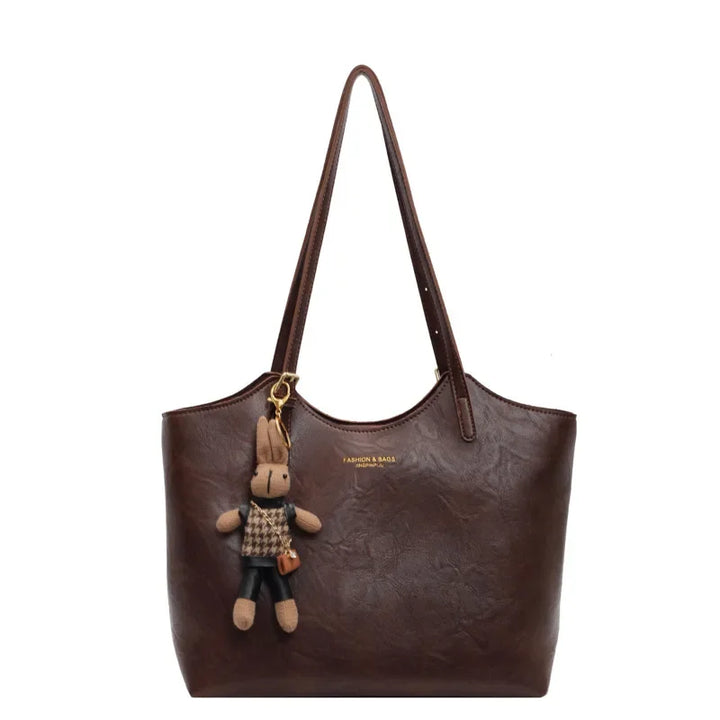 Front view of the Piper vegan leather tote bag in dark brown with a cute bunny charm and subtle branding, alternate angle