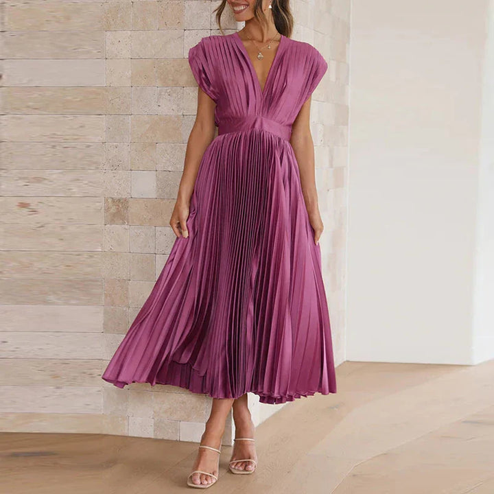 Front view, model wearing a purple Felicia pleated dress with a deep V neckline and cap sleeves